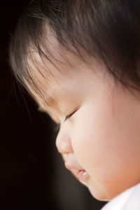 Close-up of baby girl with eyes closed against black background