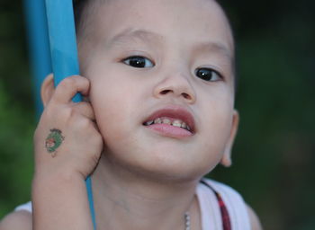 Close-up of boy leaning on pole