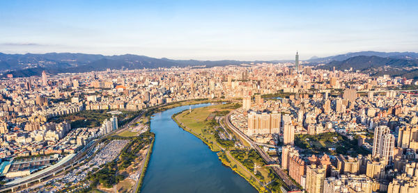 High angle view of illuminated city by river against sky