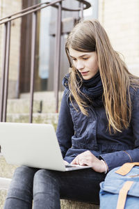 Schoolgirl using laptop on steps