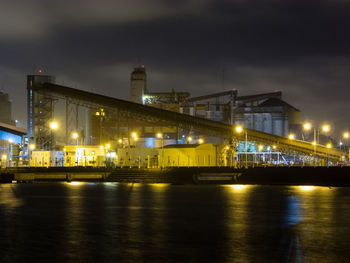 Illuminated bridge over sea against sky at night