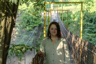 Portrait of smiling young woman standing against trees