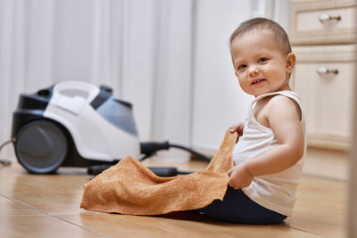 Portrait of cute baby boy sitting on floor at home
