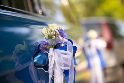 Close-up of flowers and ribbons on car door