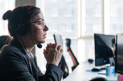 Side view of young woman using mobile phone while standing in office