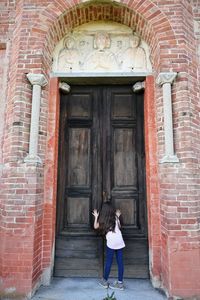 Little girl peeking through the keyhole of an ancient church door