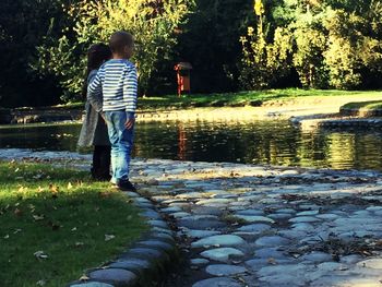 Rear view of boy standing on lake against trees