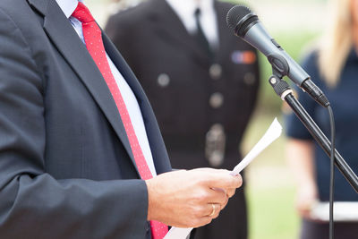 Close-up midsection of man giving speech on microphone