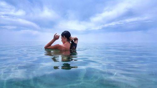 Young woman in sea against sky