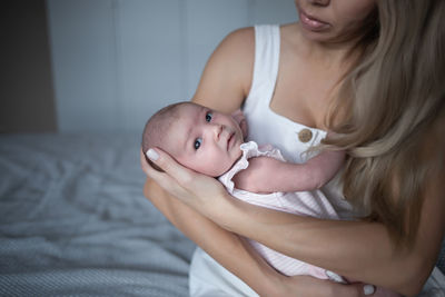 Midsection of young woman with daughter at home