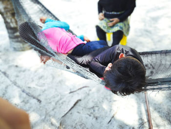 High angle view of boy on hammock by sister at beach