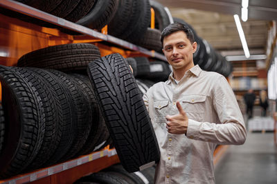 Portrait of man holding tire at store