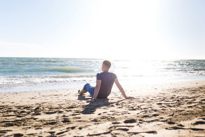 Blond guy tourist in jeans enjoying the beach and the sea