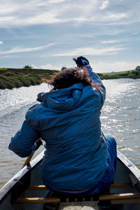 Rear view of woman sitting on boat in lake