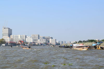 Sea by buildings against clear sky