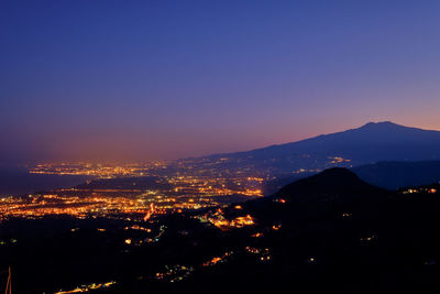 Illuminated cityscape against clear sky at night