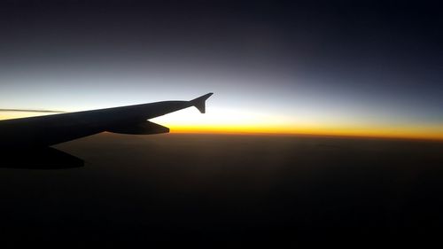 Close-up of silhouette airplane wing against sky during sunset