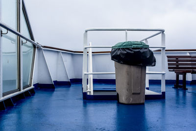 Garbage bin on ship deck with blue floor and white railings