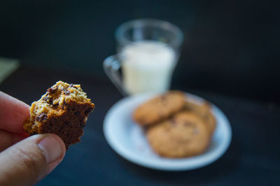 Cropped hand having cookies with milk