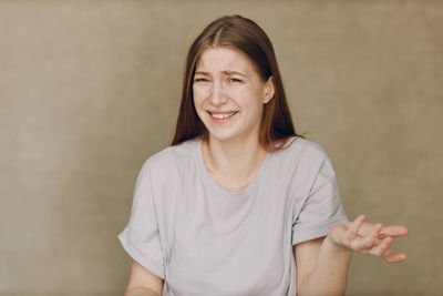 Portrait of young woman standing against wall