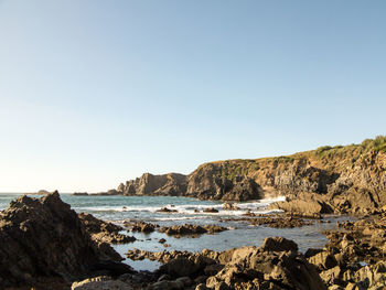 Rocks on beach against clear sky