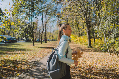 A girl in warm clothes walks through an autumn forest.