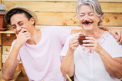 Happy grandmother and grandson standing against wooden wall