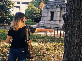 Woman feeding squirrel on field