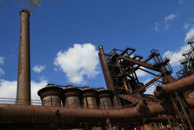 Low angle view of industry against blue sky