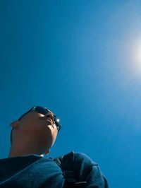 Low angle view of young man against blue sky