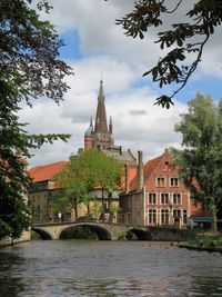 Buildings by river against sky