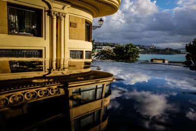 View of swimming pool by building against cloudy sky