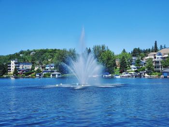 Fountain in sea against clear blue sky