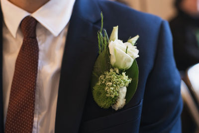 Midsection of bridegroom holding bouquet