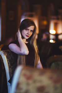 Portrait of beautiful young woman sitting on chair in room