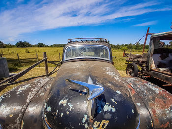 Abandoned car on field against sky