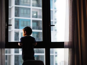 Boy looking through window at home