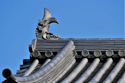 Low angle view of japanese roof tiles against blue sky