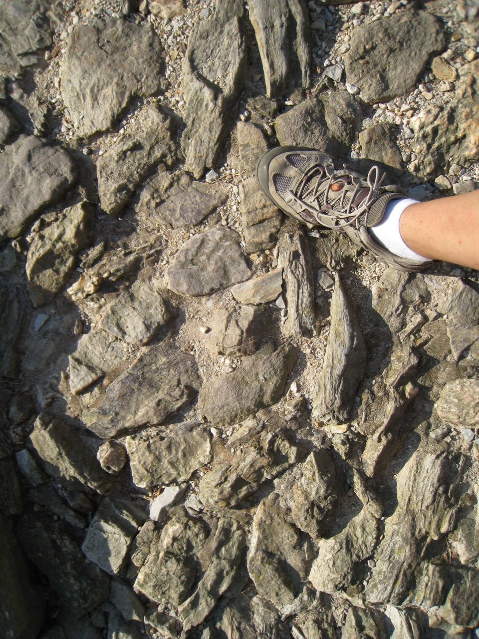 low section, person, lifestyles, leisure activity, high angle view, part of, unrecognizable person, textured, standing, rock - object, men, personal perspective, outdoors, human foot, shoe, day