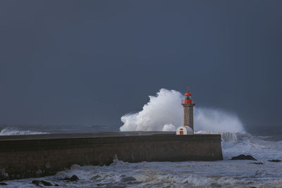 Lighthouse by sea against clear sky