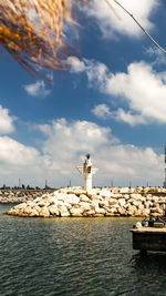 Lighthouse by sea against sky