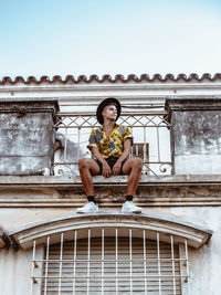 Portrait of woman sitting against built structure