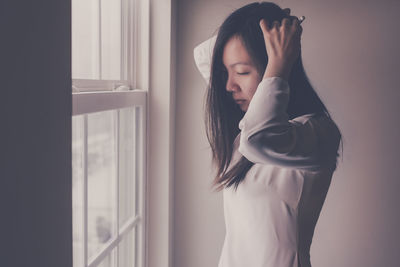 Side view of young woman wearing ao dai standing by the window