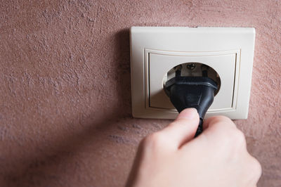 A black cord with a plug from an electrical appliance turns on or off the male hand in the socket