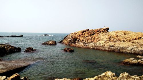 Rock formations by sea against clear sky