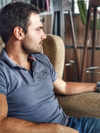 Side view of young man sitting on chair