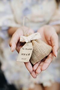 Midsection of hand holding small jute sack with text