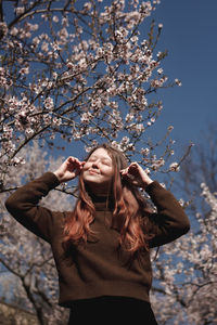 Portrait of young woman standing against bare tree