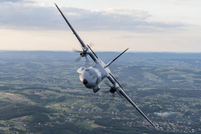 Airplane flying over landscape against sky