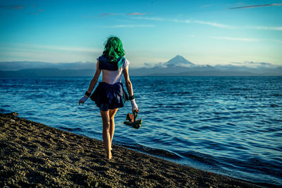 Rear view of woman standing at beach